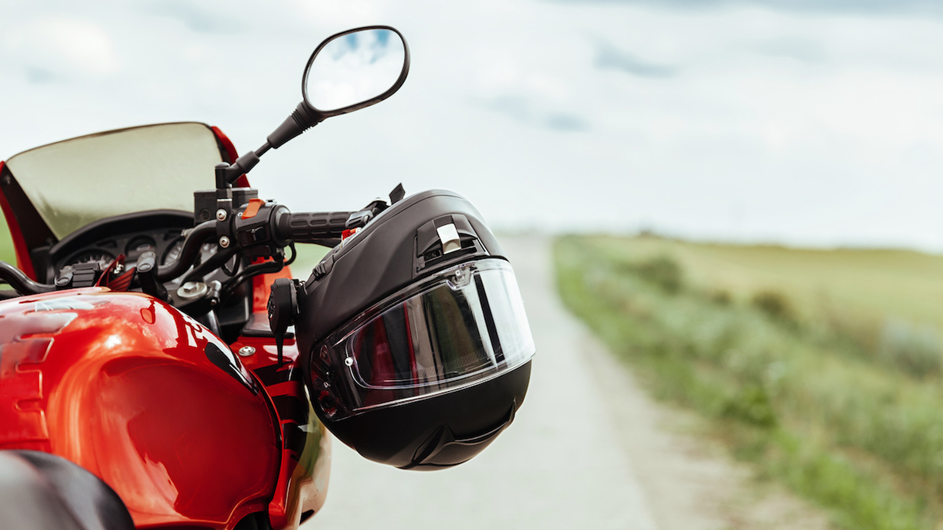 Motorcycle helmet hanging on motorcycle right steering handle.